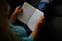 kid reading book sat on the floor