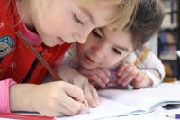 2 children writing together in book