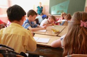 children in a classroom, with teacher at the front with a blackboard