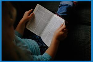 child sat on floor reading a book