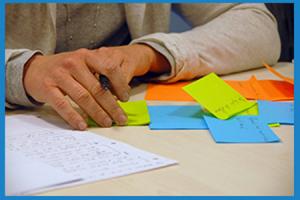 Person writing, with colourful post-it notes next to them