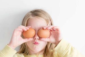 child posing with two eggs up to their eyes