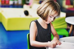 child writing in colourful classroom