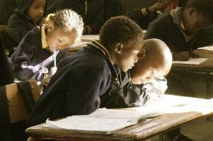 children leaning over their books, reading and writing