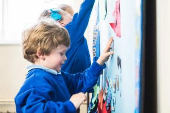 two children interacting with Mighty Writer, on the wall